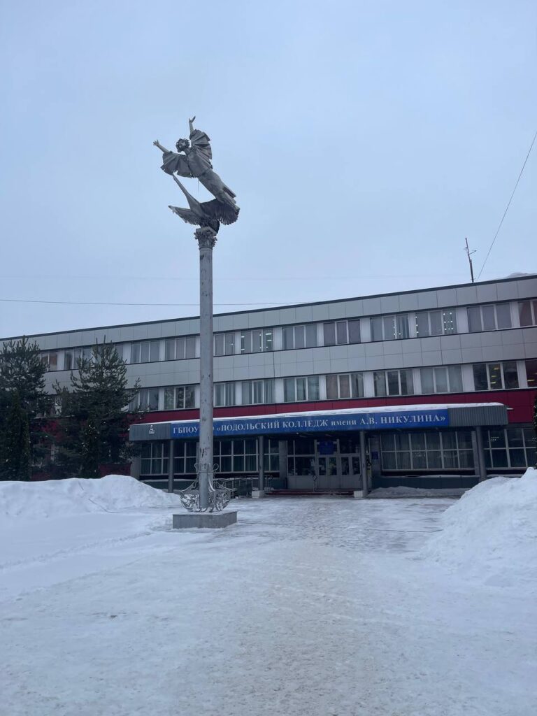 Фотография здания колледжа зимой. Учебное заведение в зимний период. Снег и памятник перед зданием.