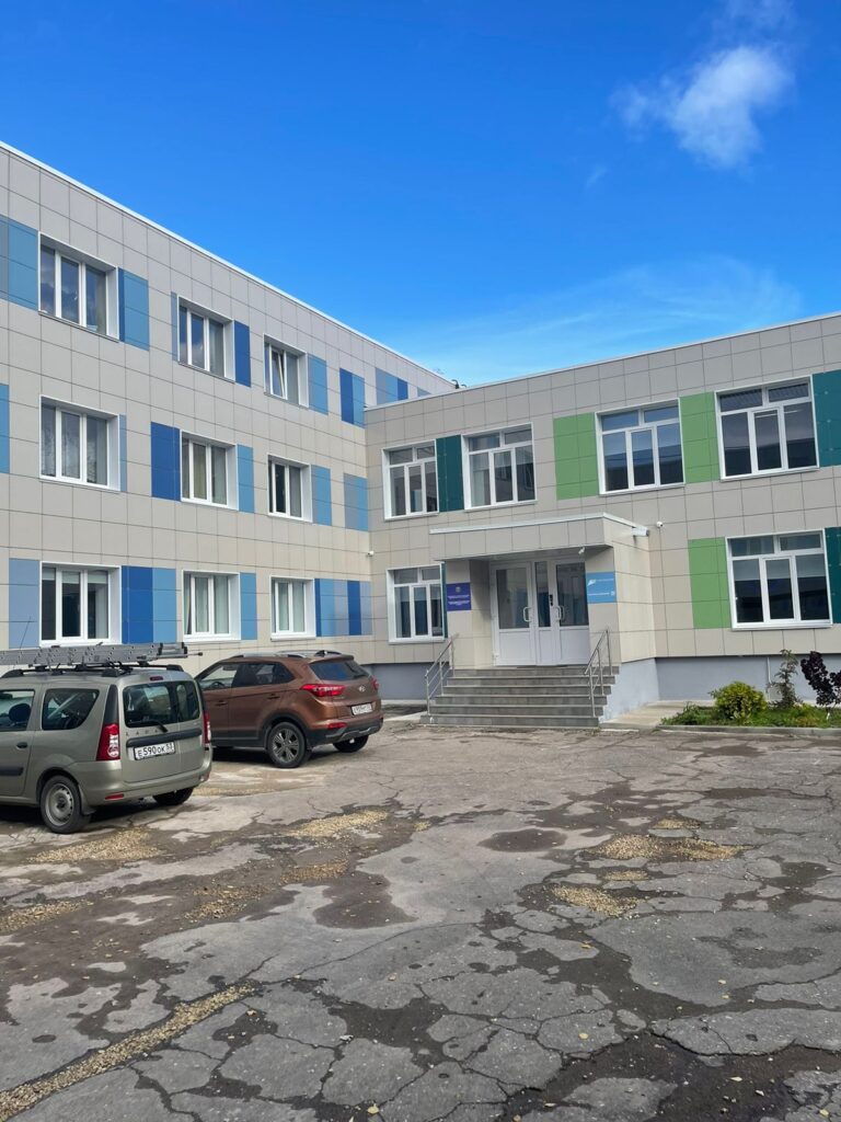 Фото фасада школы или детского сада с голубыми и зелеными акцентами. Современное учебное заведение.